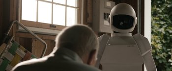 Movie still from “Robot & Frank” (2012), directed by Jake Schreier – An older man sitting in front of a robot; Medium shot, Over the shoulder angle