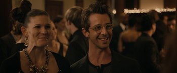 Movie still from “Robot & Frank” (2012), directed by Jake Schreier – A man in a suit and glasses smiling for the camera; Close Up shot, Over the shoulder angle