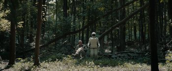 Movie still from “Robot & Frank” (2012), directed by Jake Schreier – A man sitting on the ground next to a robot in the woods; Wide shot, Over the shoulder angle