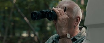 Movie still from “Robot & Frank” (2012), directed by Jake Schreier – An older man looking through a pair of binoculars; Close Up shot, Low angle