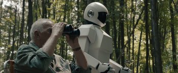Movie still from “Robot & Frank” (2012), directed by Jake Schreier – A man holding a camera and looking at a robot; Medium shot, Over the shoulder angle
