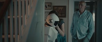 Movie still from “Robot & Frank” (2012), directed by Jake Schreier – A woman standing next to a wall holding a box; Medium shot, Over the shoulder angle