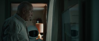 Movie still from “Robot & Frank” (2012), directed by Jake Schreier – A man standing in front of a window holding a robot; Medium shot, Over the shoulder angle