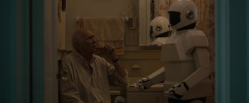 Movie still from “Robot & Frank” (2012), directed by Jake Schreier – An older man drinking a glass of wine in front of a robot; Medium shot, Over the shoulder angle