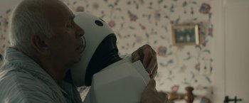 Movie still from “Robot & Frank” (2012), directed by Jake Schreier – A person holding a box with a helmet on top of it; Close Up shot, Over the shoulder angle