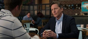 Movie still from “13 Reasons Why” (2017), created by Brian Yorkey – A man sitting at a table holding a cup of coffee; Close Up shot, Over the shoulder angle