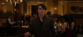 Movie still from “13 Reasons Why” (2017), created by Brian Yorkey – A man in a suit standing in front of a crowd of diners; Medium shot, Over the shoulder angle