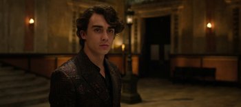 Movie still from “13 Reasons Why” (2017), created by Brian Yorkey – A young man with curly hair wearing a suit; Close Up shot, Over the shoulder angle