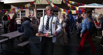 Movie still from “Rock 'n' Roll High School” (1979), directed by Joe Dante – A man holding a tray of food while standing next to a crowd of onlookers; Wide shot, Low angle