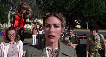 Movie still from “Rock 'n' Roll High School” (1979), directed by Joe Dante – A woman in a brown jacket is standing in front of a group of people; Medium shot, Low angle