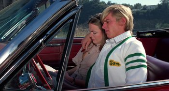 Movie still from “Rock 'n' Roll High School” (1979), directed by Joe Dante – A man and a woman sitting in the driver's seat of a car; Medium shot, High angle