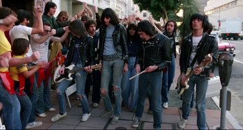 Movie still from “Rock 'n' Roll High School” (1979), directed by Joe Dante – A group of young men in leather jackets playing instruments on the street; Wide shot, Low angle