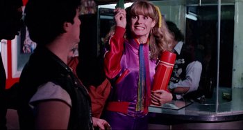 Movie still from “Rock 'n' Roll High School” (1979), directed by Joe Dante – A woman in a purple and red outfit holding a red container; Medium shot, Over the shoulder angle