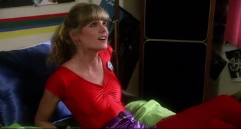Movie still from “Rock 'n' Roll High School” (1979), directed by Joe Dante – A woman in a red shirt sitting on top of a bed; Medium shot, Low angle
