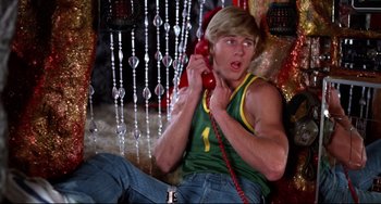 Movie still from “Rock 'n' Roll High School” (1979), directed by Joe Dante – A man sitting on the ground holding a phone to his ear; Medium shot, Overhead angle