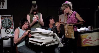 Movie still from “Rock 'n' Roll High School” (1979), directed by Joe Dante – A group of people sitting around a pile of pizza; Medium shot, Low angle