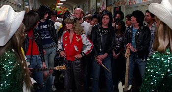 Movie still from “Rock 'n' Roll High School” (1979), directed by Joe Dante – A group of people standing around each other in a room; Medium shot, Over the shoulder angle