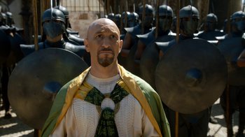 Movie still from “Game of Thrones” (2011), created by D.B. Weiss – A man with a bald head standing in front of a group of soldiers; Medium shot, Over the shoulder angle