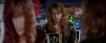 Movie still from “Rock Star” (2001), directed by Stephen Herek – A man in a leather jacket looking at himself in a mirror; Medium shot, Over the shoulder angle