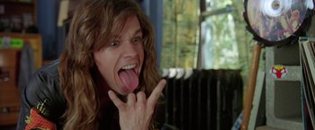 Movie still from “Rock Star” (2001), directed by Stephen Herek – A person with long hair and a tongue sticking out; Close Up shot, Low angle