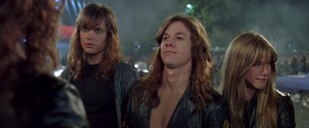 Movie still from “Rock Star” (2001), directed by Stephen Herek – A man with long brown hair stands next to another man with long brown hair; Close Up shot, Low angle