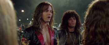 Movie still from “Rock Star” (2001), directed by Stephen Herek – A man with long brown hair and a man with curly brown hair; Close Up shot, Low angle