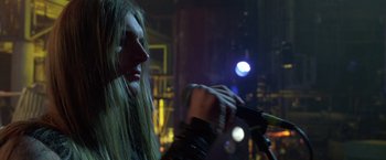 Movie still from “Rock Star” (2001), directed by Stephen Herek – A man with long hair is holding a microphone; Close Up shot, Low angle