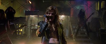 Movie still from “Rock Star” (2001), directed by Stephen Herek – A man in a leather jacket is holding a camera; Medium shot, Low angle