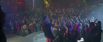 Movie still from “Rock Star” (2001), directed by Stephen Herek – A group of people standing in front of an audience; Wide shot, High angle