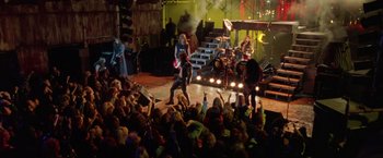 Movie still from “Rock Star” (2001), directed by Stephen Herek – A crowd of people watching a band perform on a stage; Wide shot, High angle