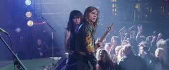 Movie still from “Rock Star” (2001), directed by Stephen Herek – A couple of people that are playing a guitar; Medium shot, Low angle