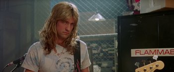 Movie still from “Rock Star” (2001), directed by Stephen Herek – A man with long blonde hair wearing a white t - shirt; Close Up shot, Low angle