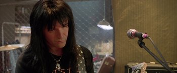 Movie still from “Rock Star” (2001), directed by Stephen Herek – A man with long black hair wearing a black t - shirt; Close Up shot, Over the shoulder angle