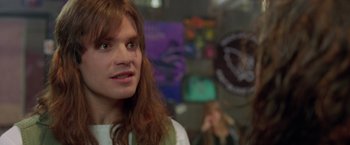Movie still from “Rock Star” (2001), directed by Stephen Herek – A man with long red hair is looking at the camera; Close Up shot, Over the shoulder angle