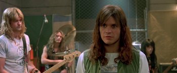 Movie still from “Rock Star” (2001), directed by Stephen Herek – A man with long brown hair standing next to a woman with long brown hair; Close Up shot, Over the shoulder angle