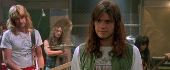 Movie still from “Rock Star” (2001), directed by Stephen Herek – A man with long brown hair standing in front of another man with long brown hair; Close Up shot, Over the shoulder angle