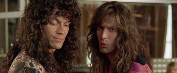 Movie still from “Rock Star” (2001), directed by Stephen Herek – A man with long hair is looking at another man with long hair; Close Up shot, Low angle