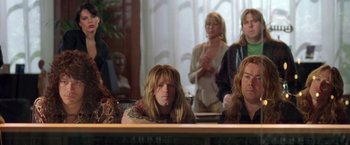 Movie still from “Rock Star” (2001), directed by Stephen Herek – A group of people sitting at a table; Medium shot, Low angle