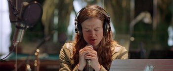 Movie still from “Rock Star” (2001), directed by Stephen Herek – A woman wearing headphones and holding her hands in prayer; Close Up shot, Low angle
