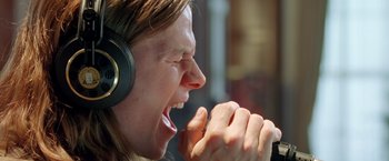 Movie still from “Rock Star” (2001), directed by Stephen Herek – A person with headphones on and mouth wide open; Close Up shot, Overhead angle