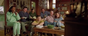 Movie still from “Rock Star” (2001), directed by Stephen Herek – A group of people sitting around a living room table; Wide shot, High angle