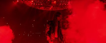 Movie still from “Rock Star” (2001), directed by Stephen Herek – A man standing in front of a stage lit up with red lights; Wide shot, High angle
