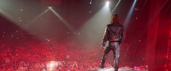 Movie still from “Rock Star” (2001), directed by Stephen Herek – A man standing on a stage in front of an audience; Wide shot, Low angle