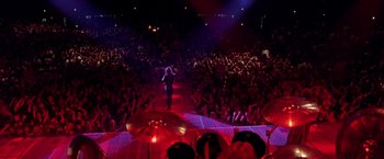 Movie still from “Rock Star” (2001), directed by Stephen Herek – A crowd of people watching a person on a stage; Extreme Wide shot, High angle