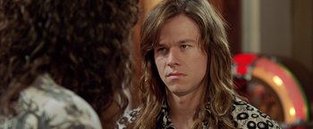 Movie still from “Rock Star” (2001), directed by Stephen Herek – A man with long brown hair wearing a leopard print shirt; Close Up shot, Over the shoulder angle