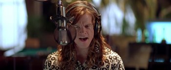 Movie still from “Rock Star” (2001), directed by Stephen Herek – A woman wearing headphones is singing into a microphone; Close Up shot, Low angle