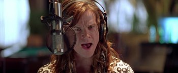 Movie still from “Rock Star” (2001), directed by Stephen Herek – A woman with long red hair is singing into a microphone; Close Up shot, Low angle