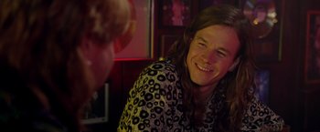 Movie still from “Rock Star” (2001), directed by Stephen Herek – A man with long brown hair smiles at the camera; Close Up shot, Over the shoulder angle