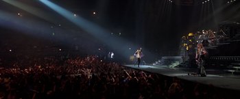 Movie still from “Rock Star” (2001), directed by Stephen Herek – A crowd of people in a dark room with lights on; Extreme Wide shot, High angle