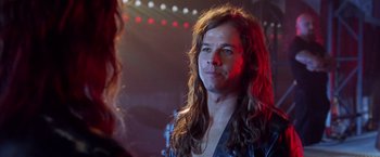 Movie still from “Rock Star” (2001), directed by Stephen Herek – A man with long hair is looking at the camera; Close Up shot, Over the shoulder angle